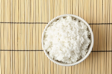 Photo of Boiled rice in bowl on bamboo mat, top view with space for text