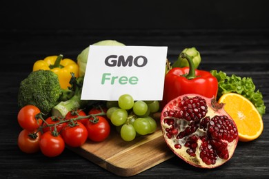 Photo of Tasty fresh GMO free products and paper card on black wooden table