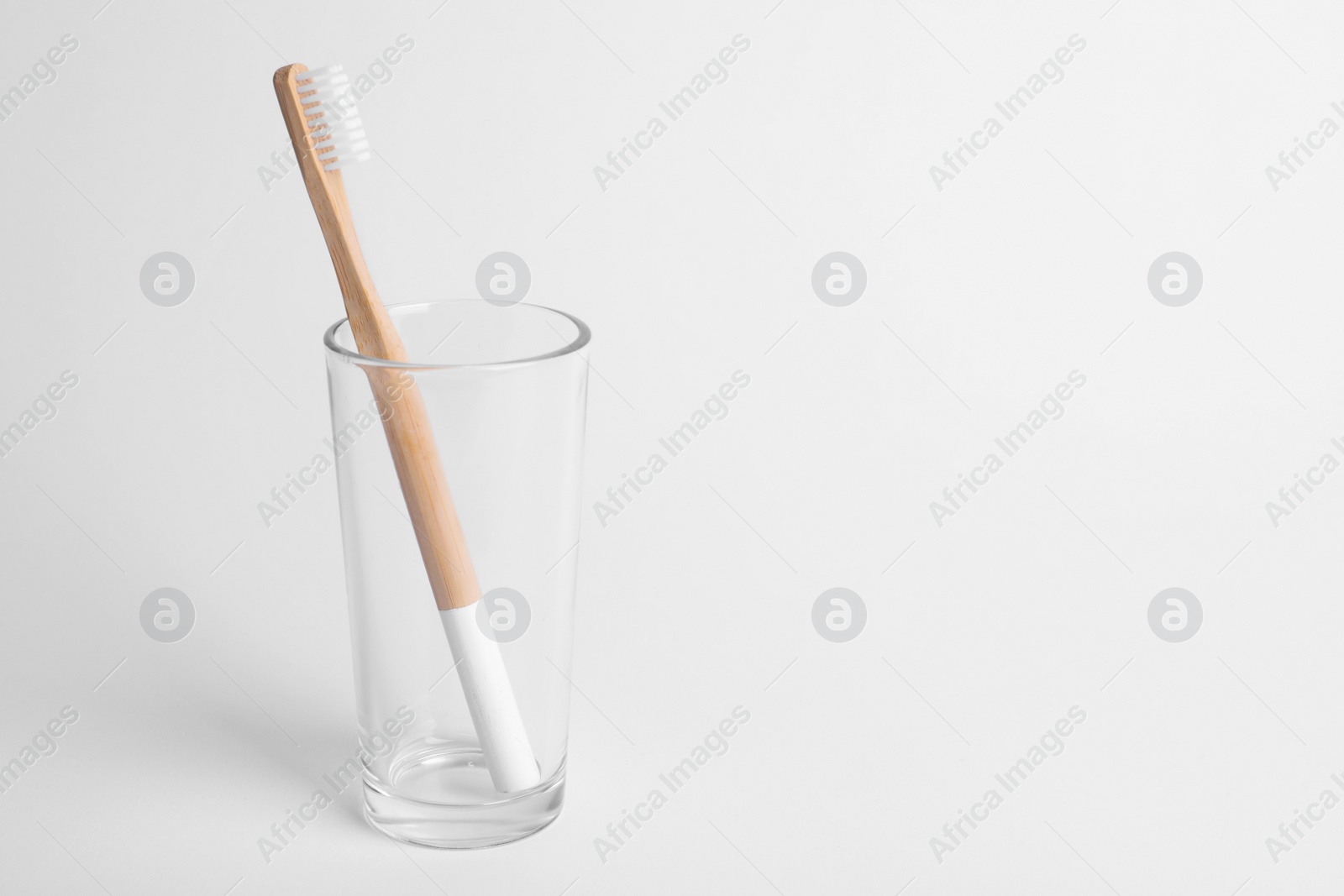 Photo of Glass with bamboo toothbrush on white background. Space for text