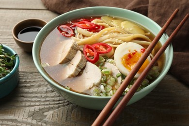 Photo of Delicious ramen in bowl on wooden table, closeup. Noodle soup