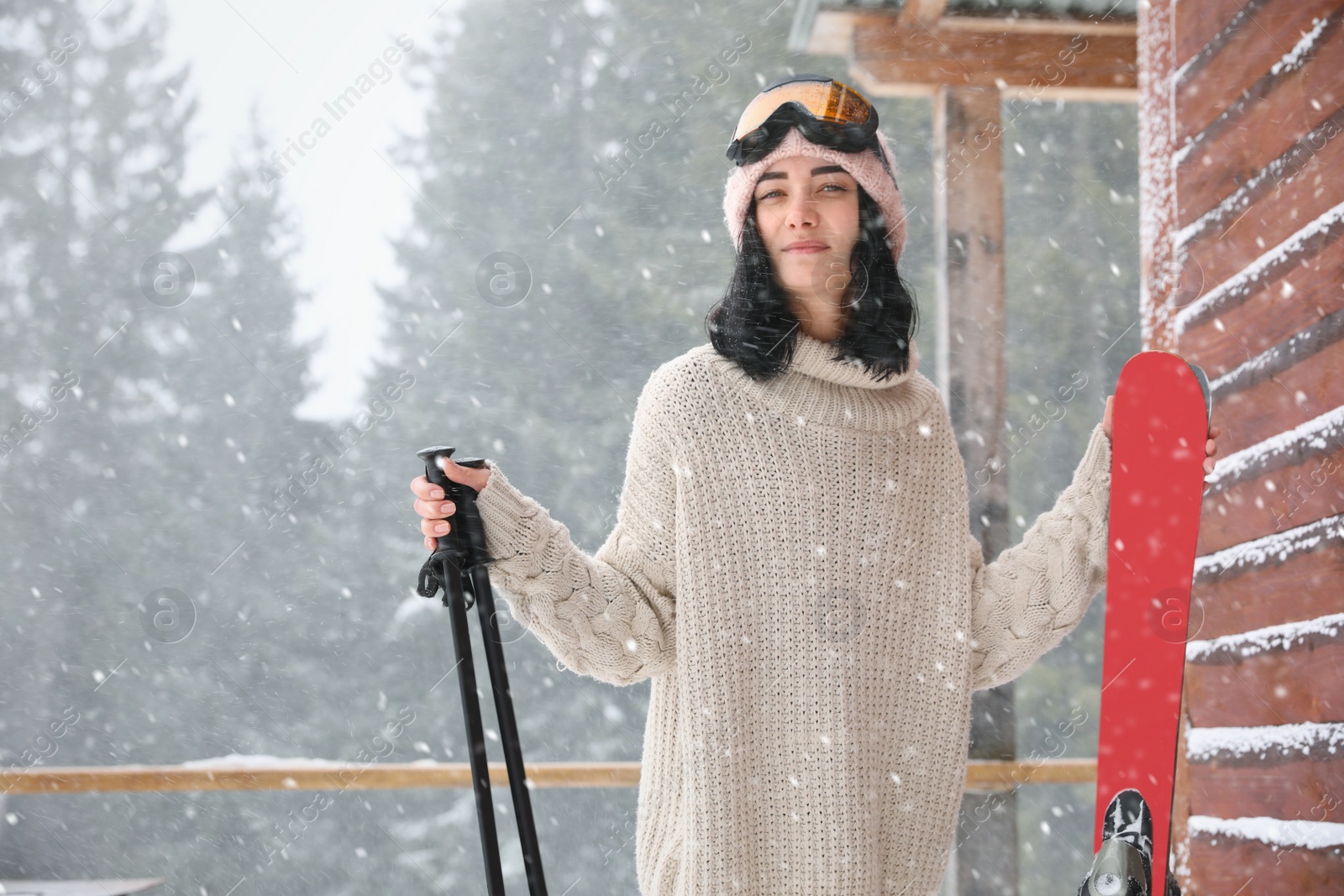 Photo of Young woman with skis wearing winter sport clothes and goggles outdoors