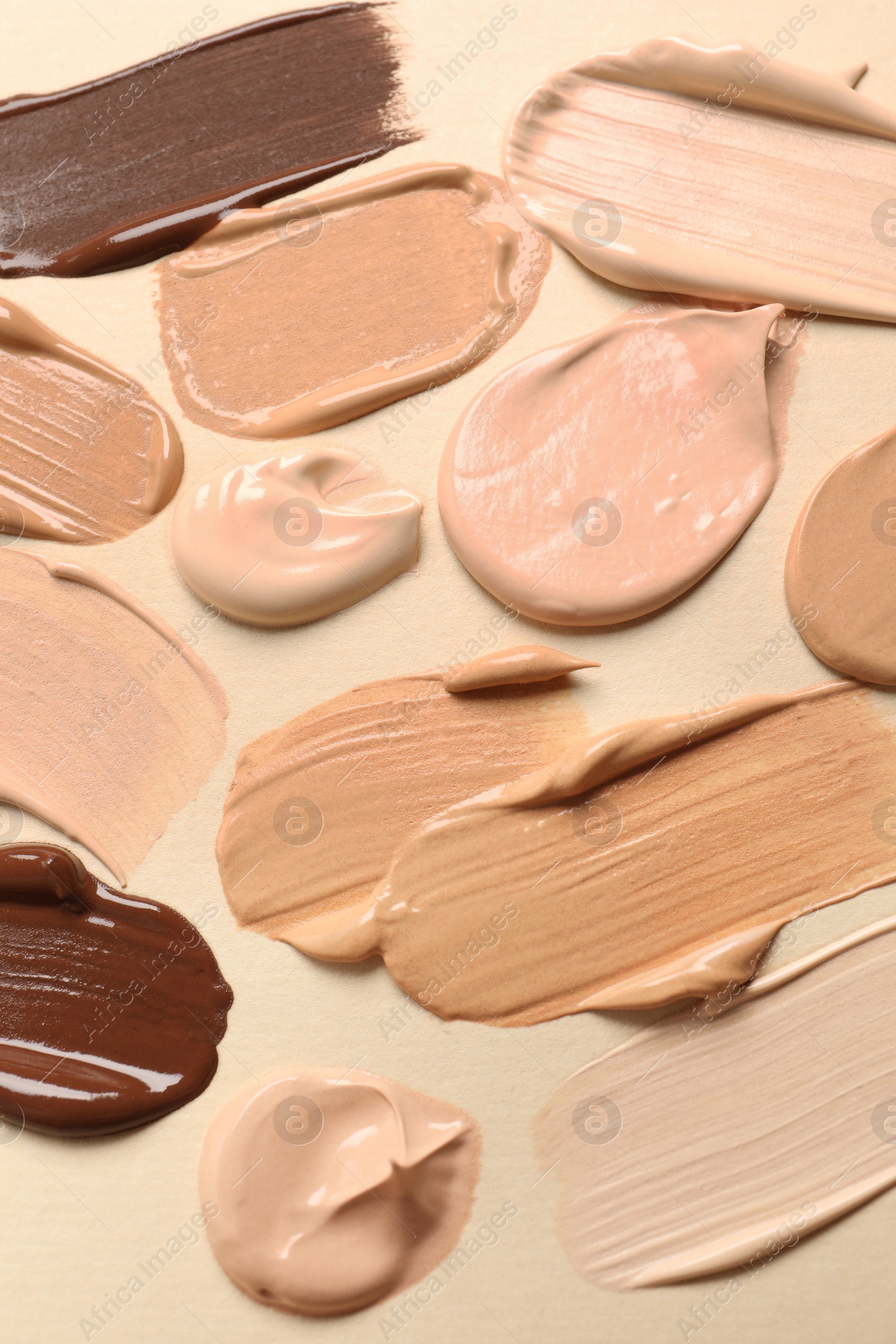 Photo of Samples of skin foundation on beige background, closeup