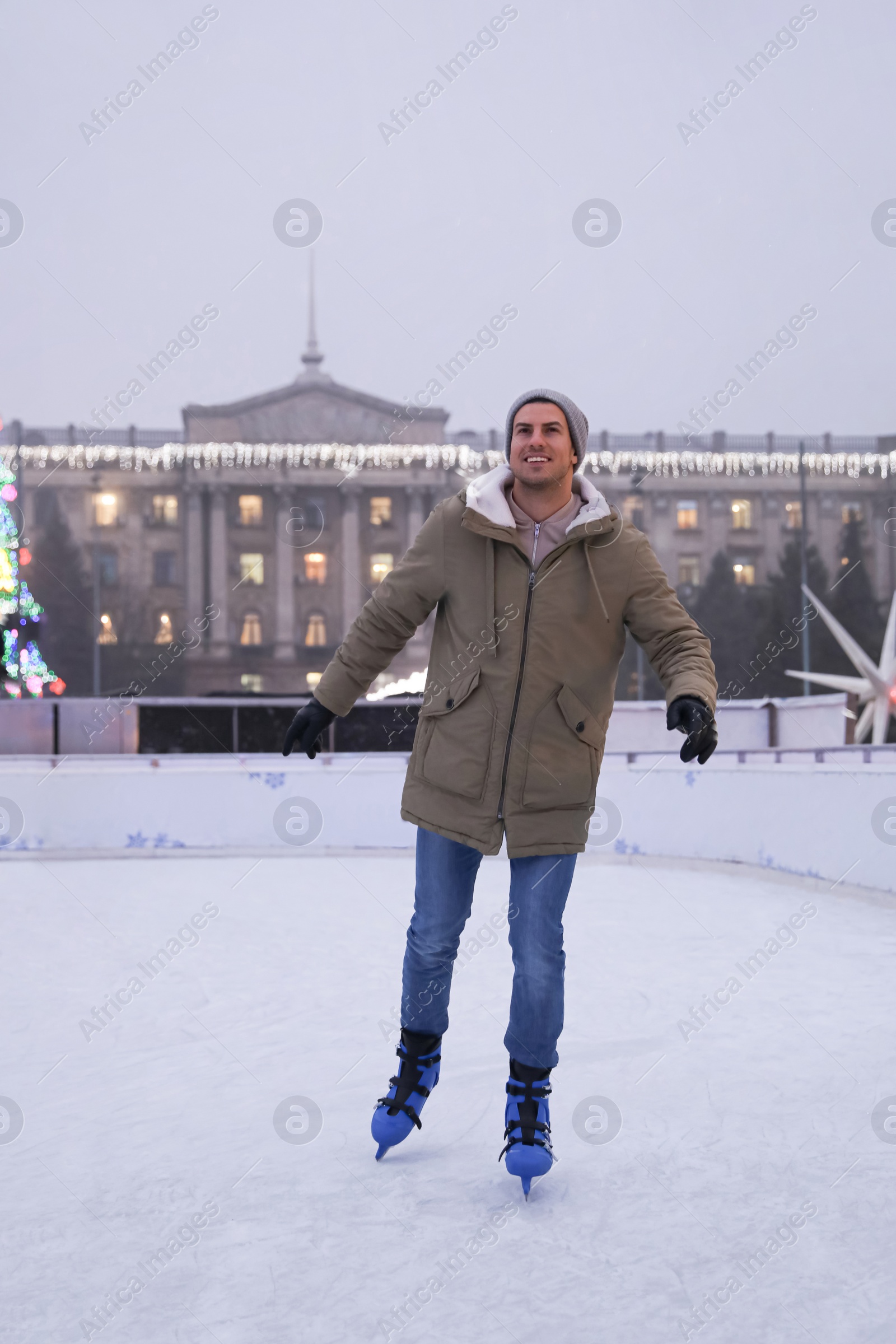 Image of Happy man skating at outdoor ice rink