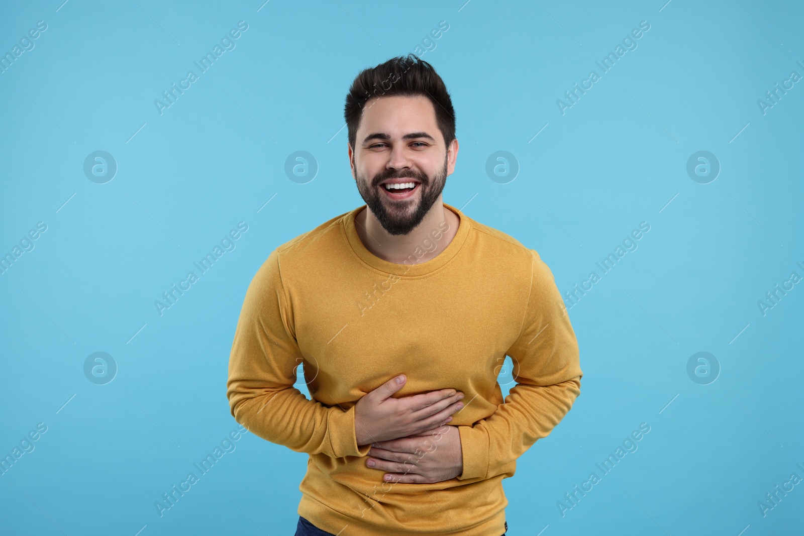 Photo of Handsome young man laughing on light blue background