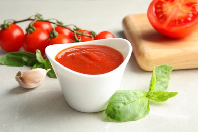 Photo of Composition with bowl of tomato sauce on light table