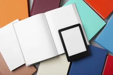 Portable e-book reader on hardcover books on grey table, flat lay