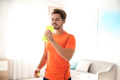 Young sporty man with bottle of protein shake at home