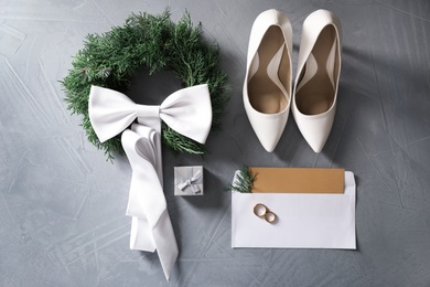 Photo of Flat lay composition with wedding rings, white high heel shoes and decor on grey background