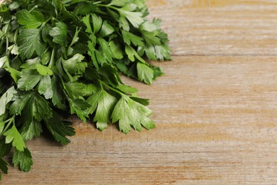 Photo of Bunch of fresh green parsley leaves on light wooden table, closeup. Space for text