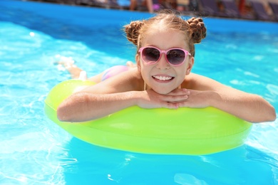 Photo of Little girl with inflatable ring in swimming pool