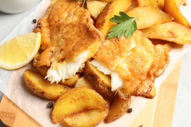 British traditional fish and potato chips on wooden board, closeup