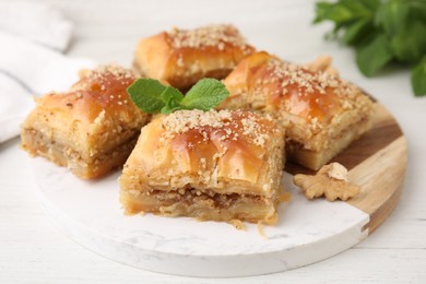 Photo of Eastern sweets. Pieces of tasty baklava on white wooden table, closeup