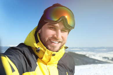 Photo of Happy young man taking selfie in mountains. Winter vacation