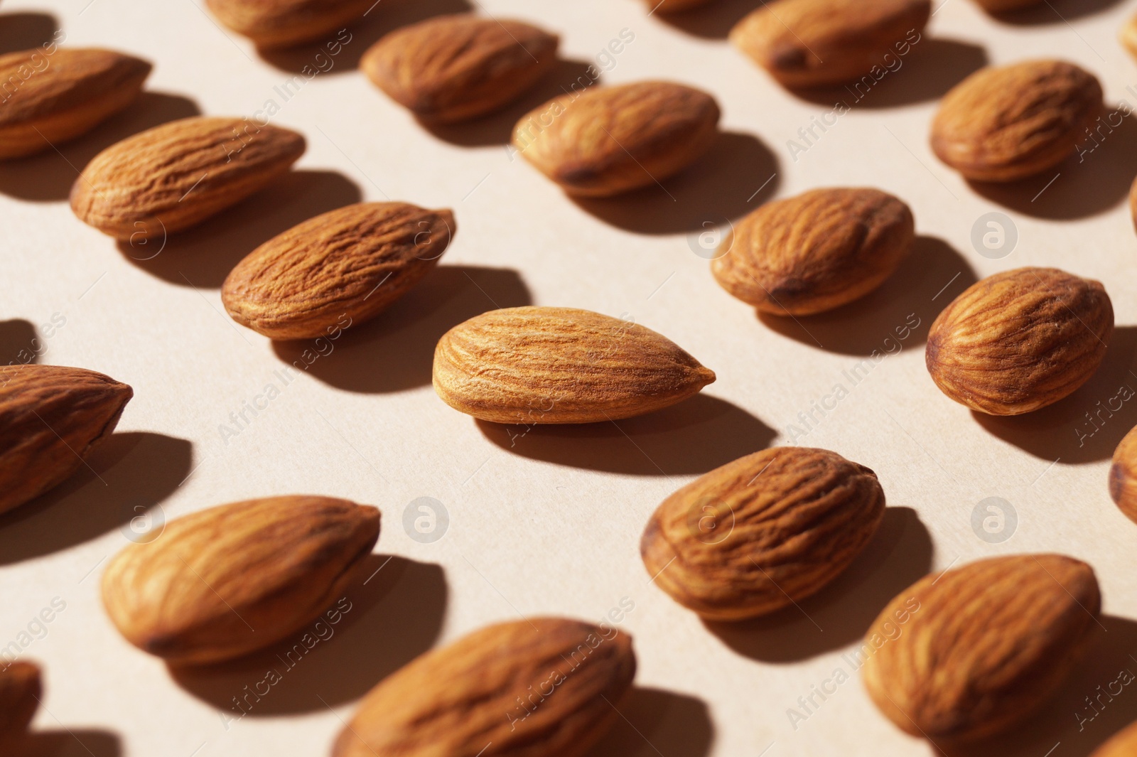 Photo of Delicious raw almonds on beige background, closeup