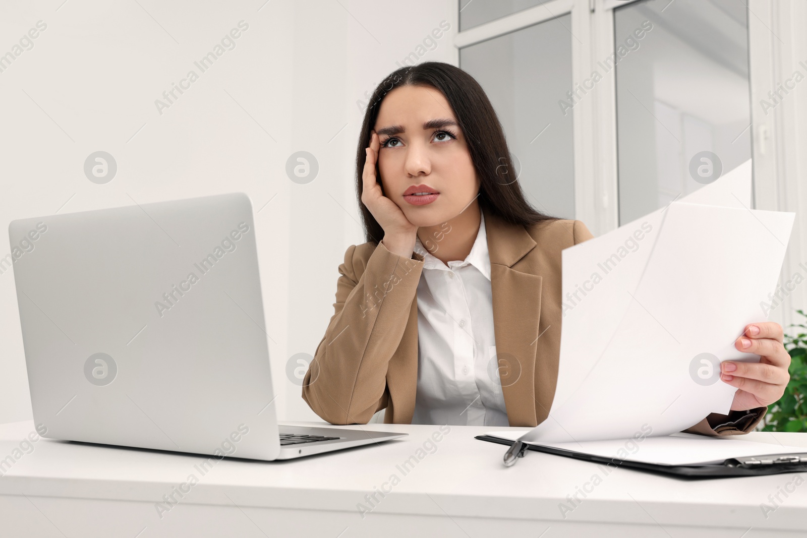 Photo of Unhappy young female intern at table in office