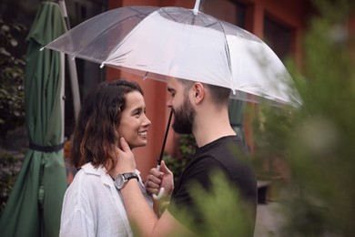 Photo of Young couple with umbrella enjoying time together under rain on city street