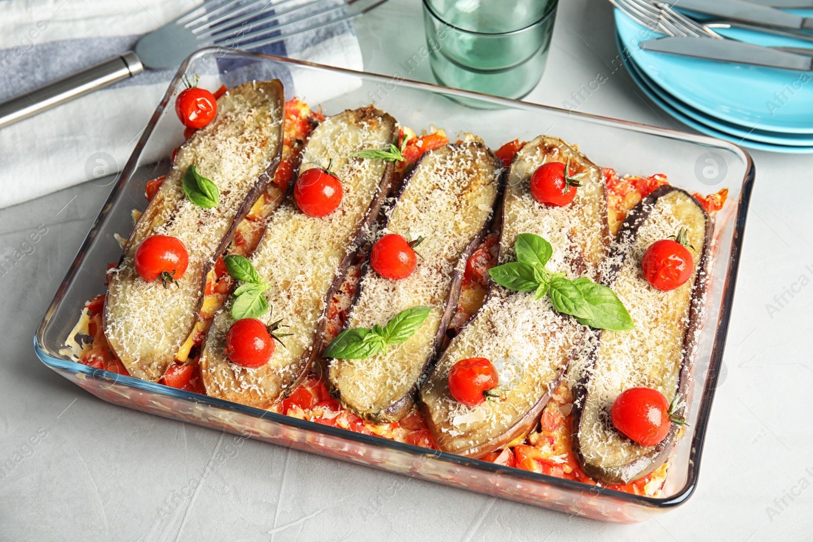 Photo of Baked eggplant with tomatoes, cheese and basil in dishware on table