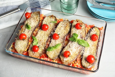 Baked eggplant with tomatoes, cheese and basil in dishware on table