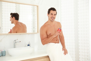 Photo of Handsome young man with deodorant in bathroom