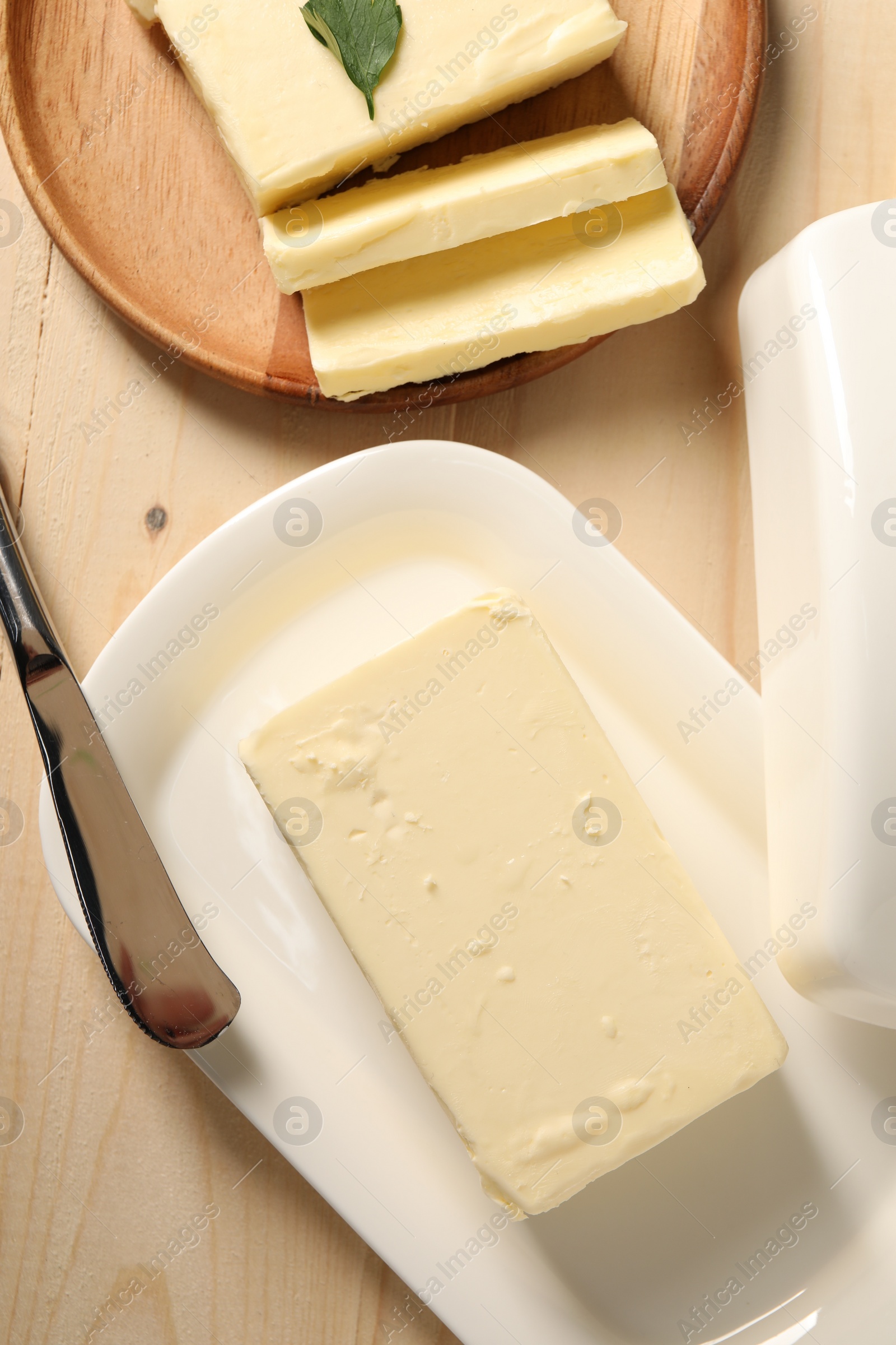 Photo of Tasty butter and knife on wooden table, flat lay