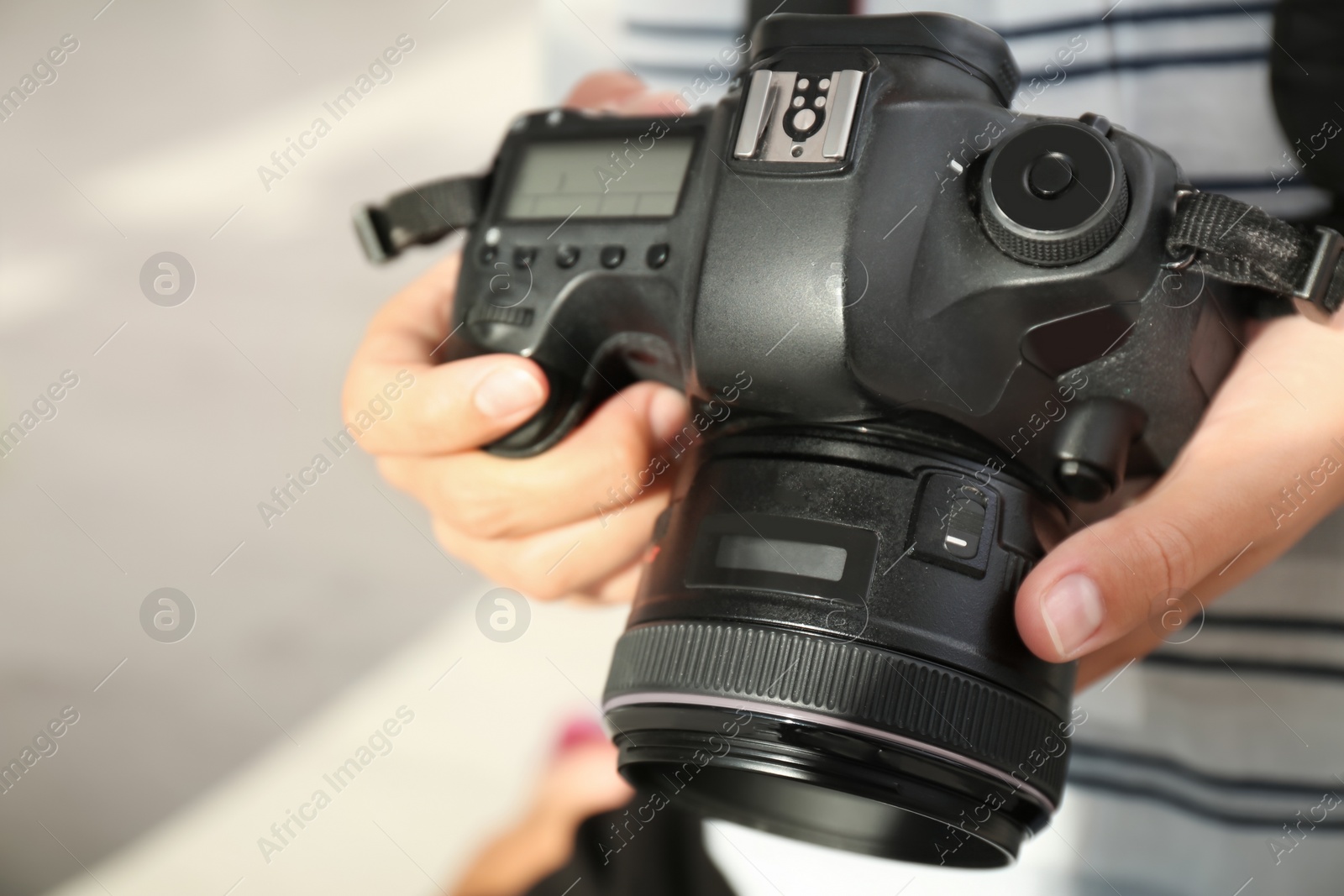 Photo of Female photographer with professional camera on blurred background, closeup