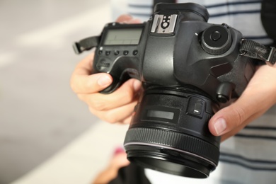 Female photographer with professional camera on blurred background, closeup