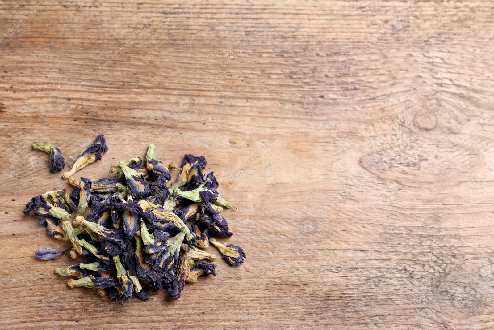 Photo of Pile of dry organic blue Anchan on wooden table, flat lay with space for text. Herbal tea