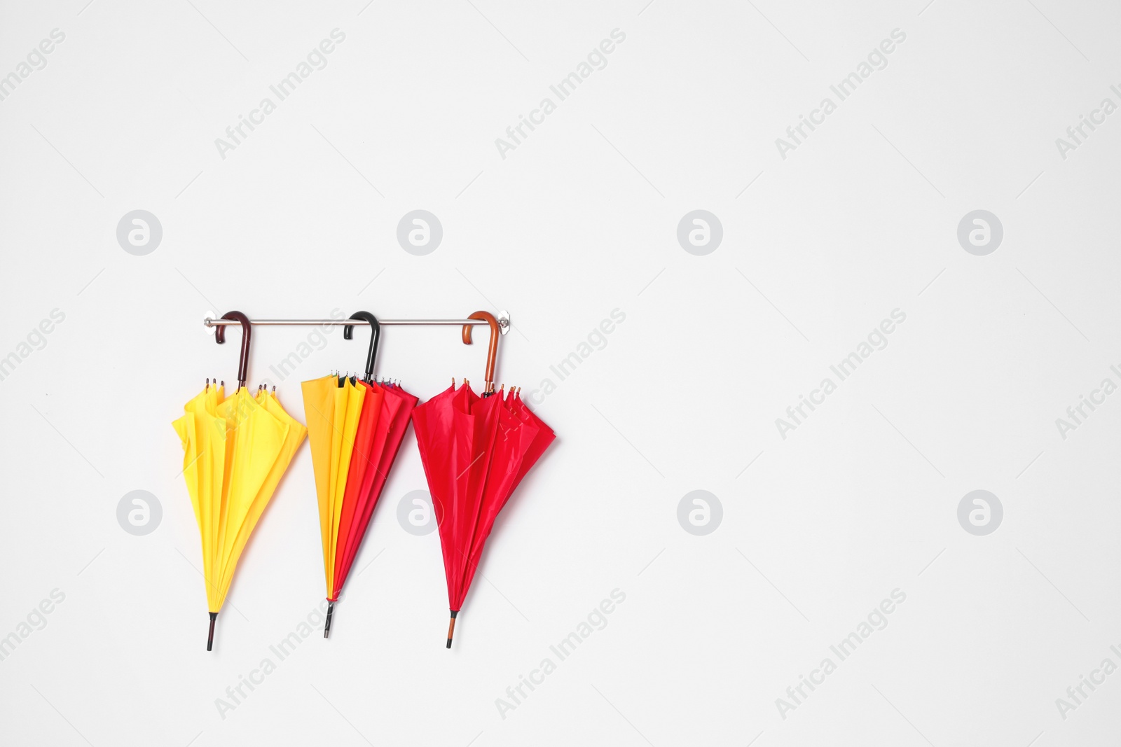 Photo of Beautiful bright umbrellas hanging on wall with space for design