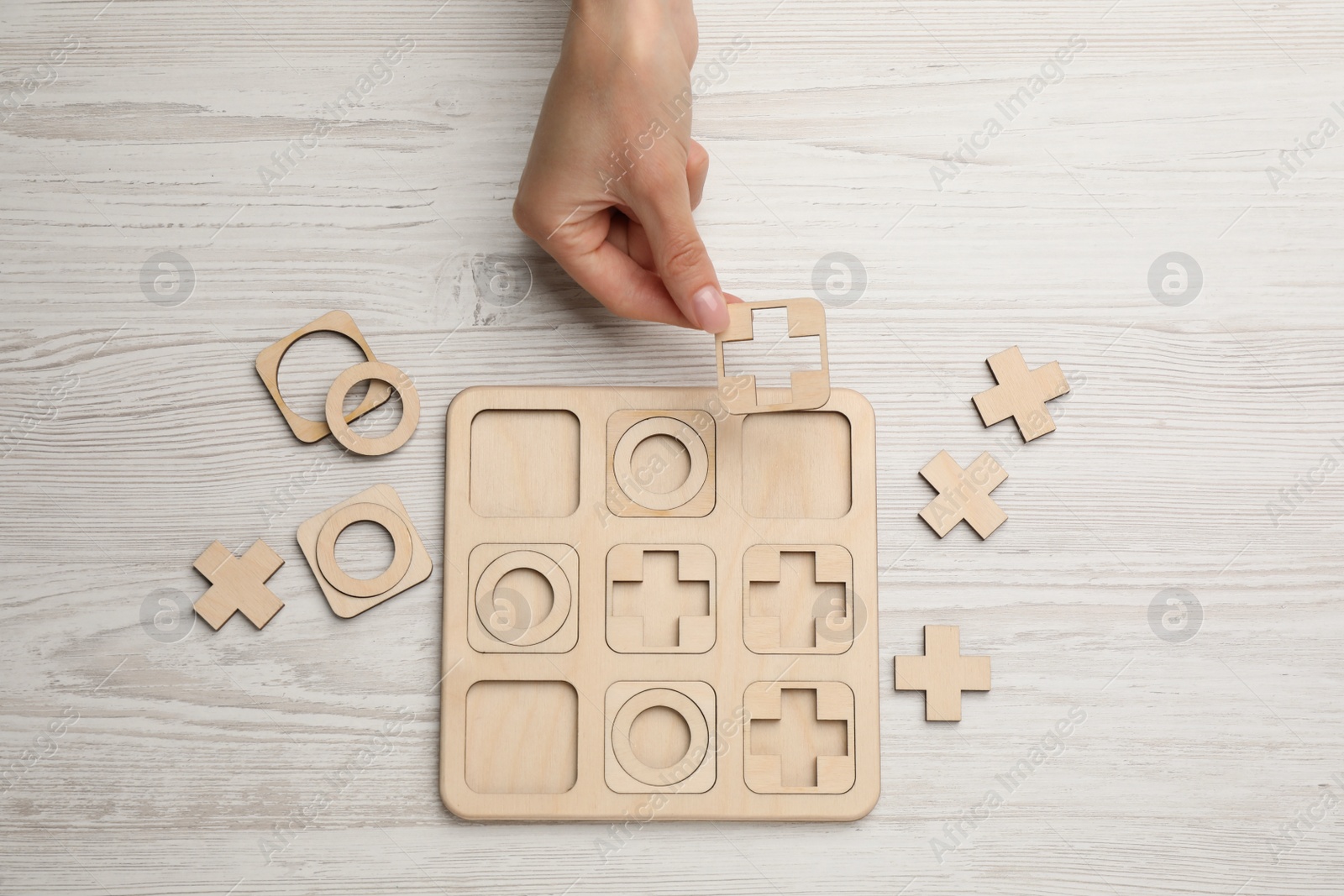 Photo of Woman playing tic tac toe game at white wooden table, top view