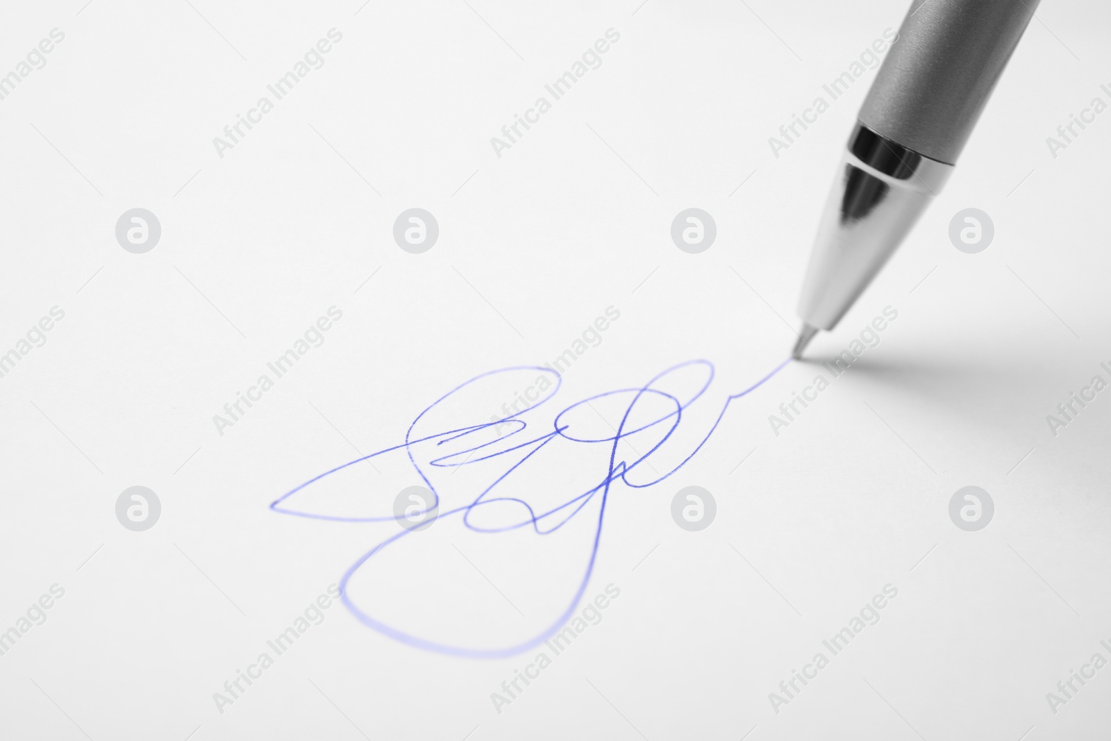 Photo of Signing on sheet of white paper with pen, closeup