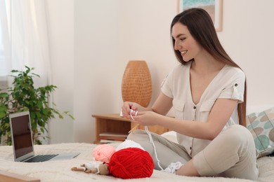 Photo of Young woman learning to knit with online course at home, space for text. Handicraft hobby