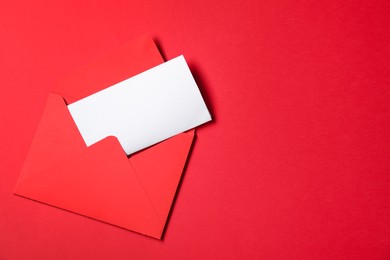 Photo of Letter envelope with card on red background, top view. Space for text