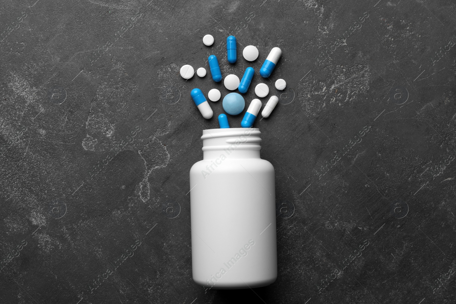 Photo of Bottle with different pills on grey background, flat lay