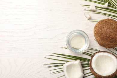 Flat lay composition with coconut oil on white wooden table, space for text