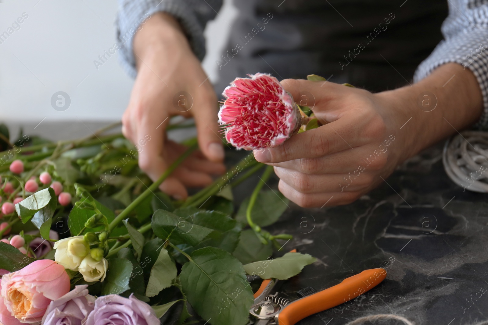 Photo of Male florist creating beautiful bouquet at table, closeup