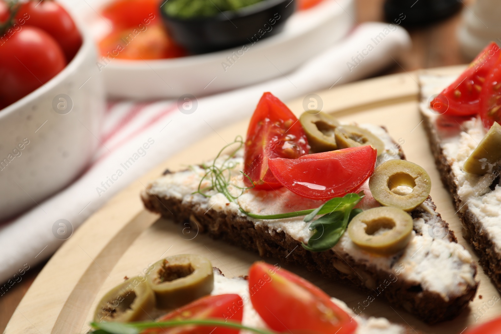 Photo of Delicious ricotta bruschettas with fresh tomatoes, olives and greens on table