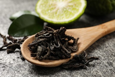 Photo of Dry bergamot tea leaves and fresh fruit on grey table, closeup