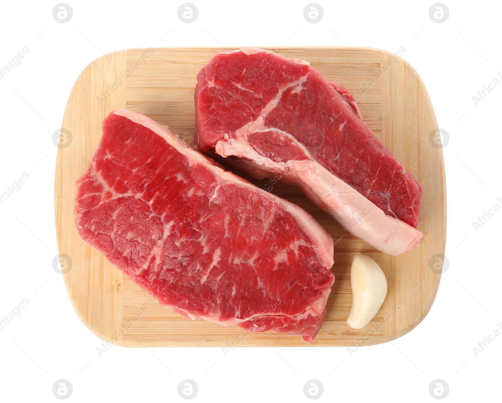 Photo of Board with steaks of raw beef meat and garlic clove isolated on white, top view