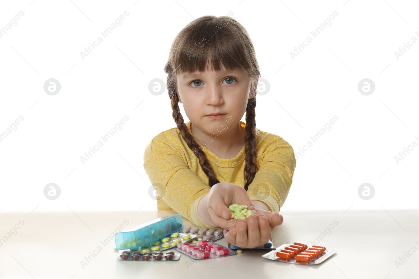 Photo of Little child with many different pills on white background. Danger of medicament intoxication