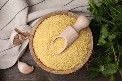 Photo of Couscous in bowl, scoop, parsley and garlic on table, flat lay