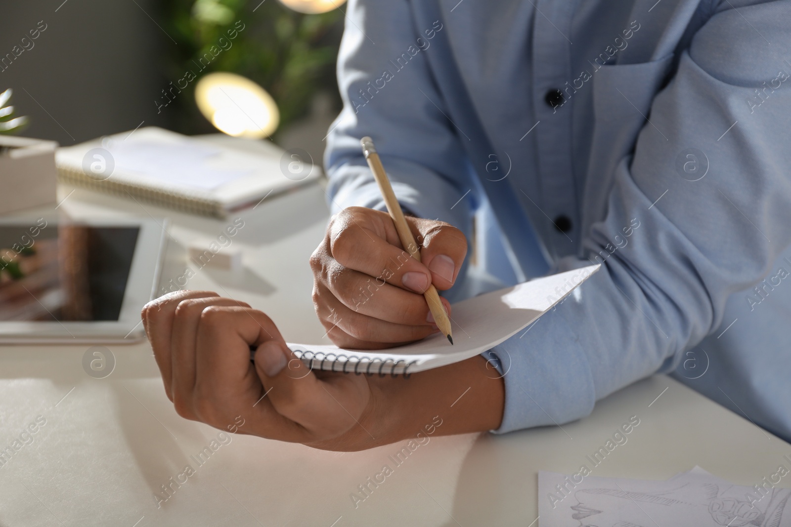 Photo of Man drawing with pencil in notepad at table, closeup