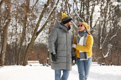 Beautiful happy couple walking in snowy park on winter day