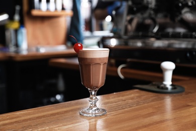 Photo of Glass of coffee drink with cherry on bar counter