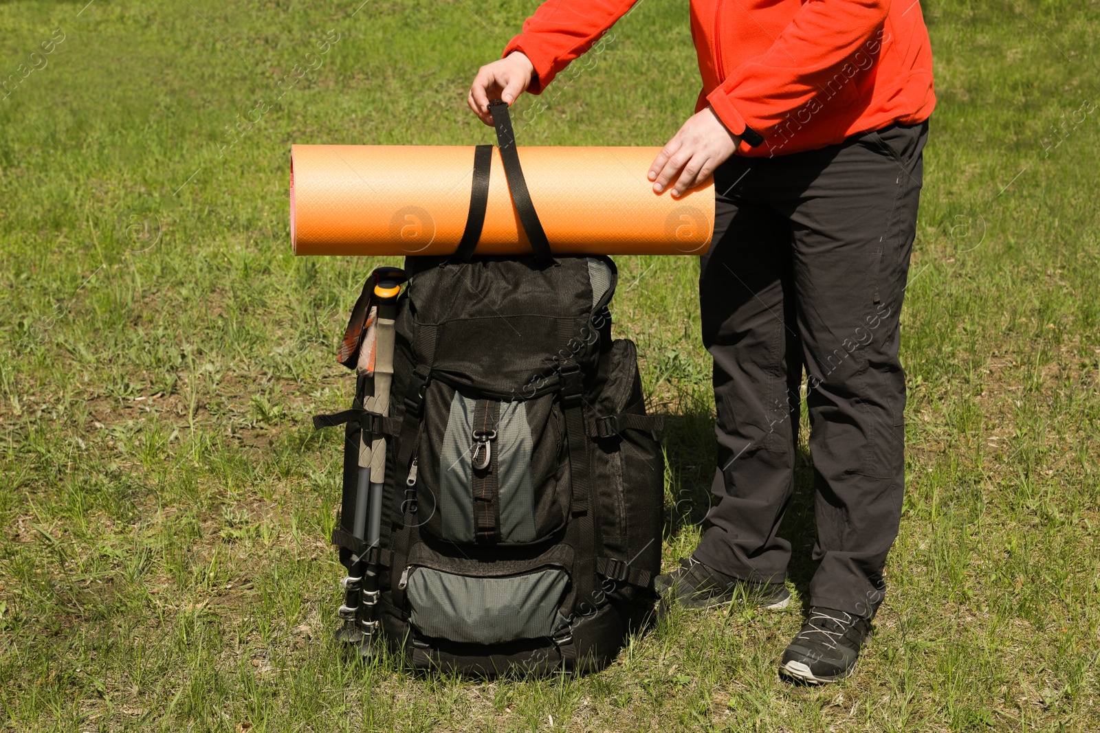 Photo of Hiker fastening mat on backpack outdoors, closeup