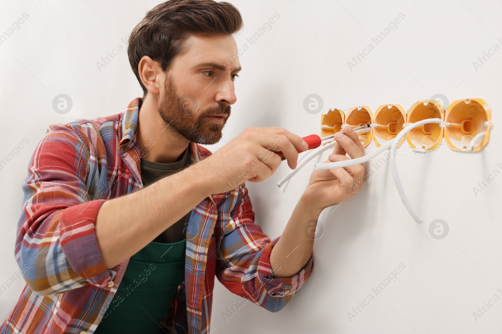 Photo of Professional electrician with screwdriver fixing wires indoors