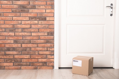 Cardboard parcel box on floor near apartment entrance. Mockup for design