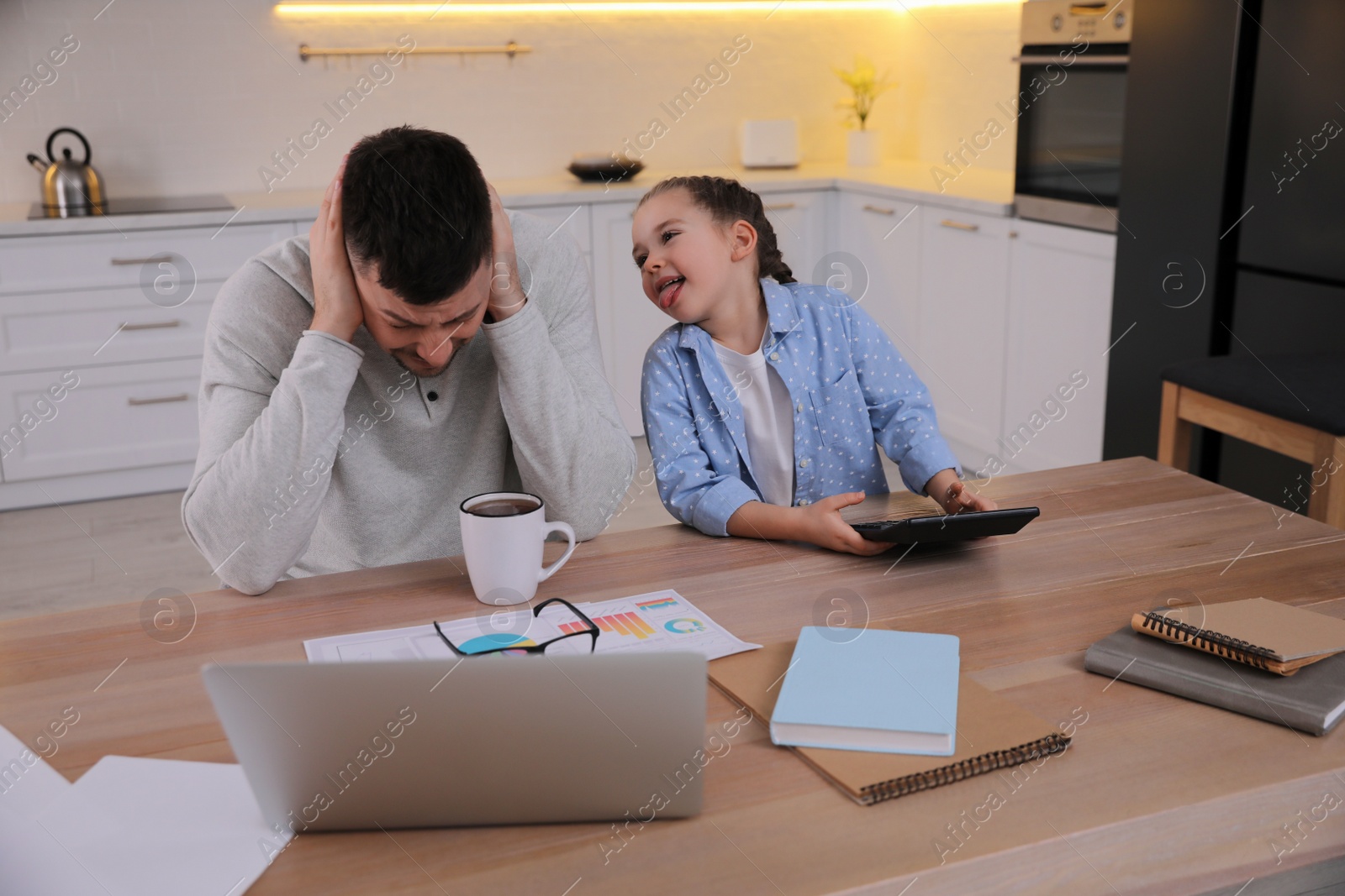 Photo of Overwhelmed man combining parenting and work at home