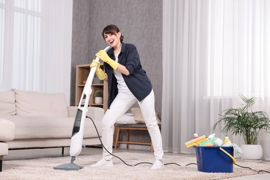 Happy young housewife having fun while cleaning carpet at home