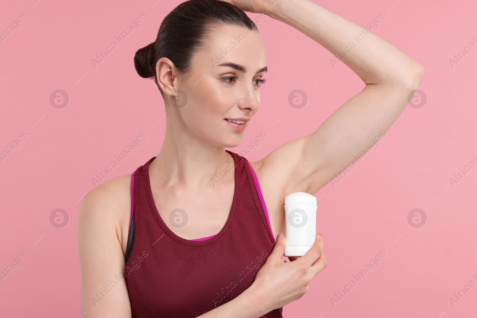 Photo of Beautiful woman applying deodorant on pink background