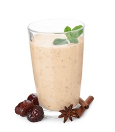 Glass of delicious date smoothie with mint, dried fruits, anise and cinnamon stick on white background